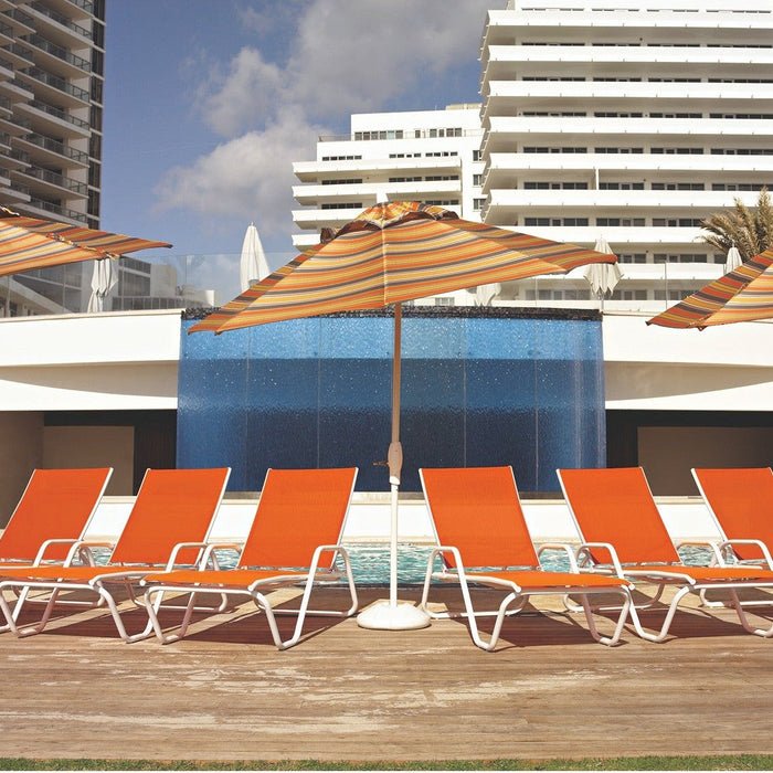 Rows of Telescope Casual Gardenella sling chaise lounges in orange beside a resort pool