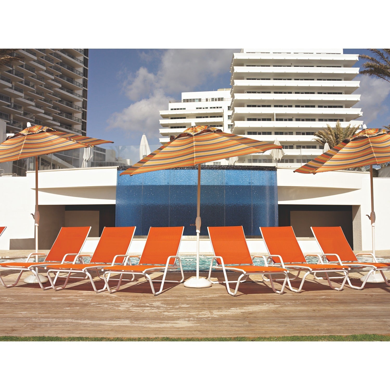 Rows of Telescope Casual Gardenella sling chaise lounges in orange beside a resort pool