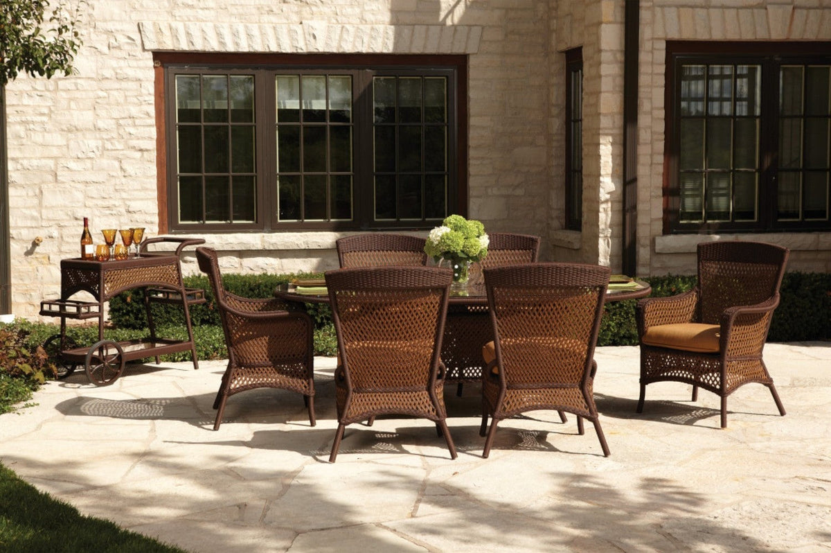 Lloyd Flanders Grand Traverse caramel wicker dining chairs around an oval table on a stone patio