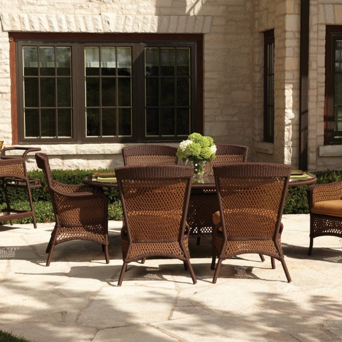 Lloyd Flanders Grand Traverse caramel wicker dining chairs around an oval table on a stone patio