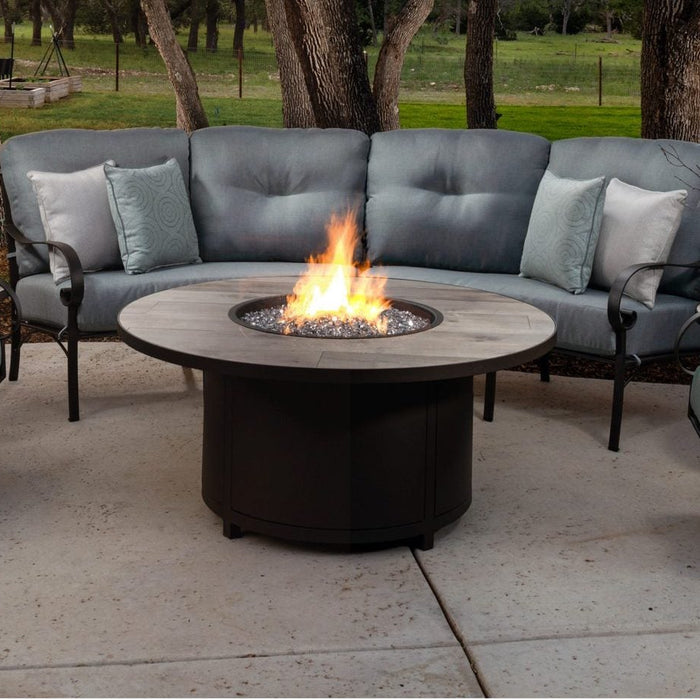 O.W. Lee Pasadera curved sectional, swivel rocker and spring base chair around a round fire table under oak trees