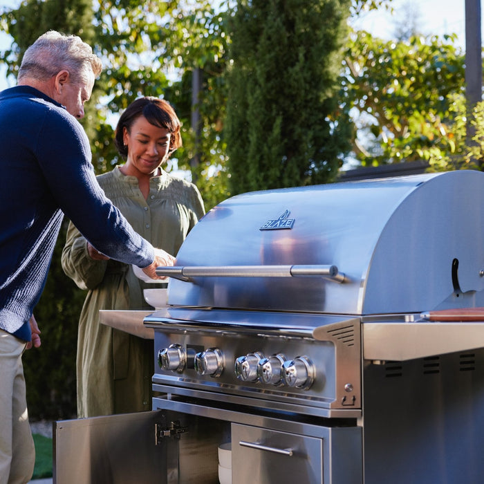 Couple cooking on a Blaze LTE PRO 32 inch gas grill on its stainless cart
