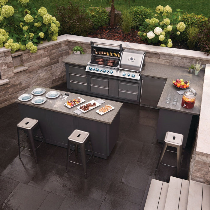 U-shaped outdoor kitchen island with a built-in grill and bar seating in a stone courtyard