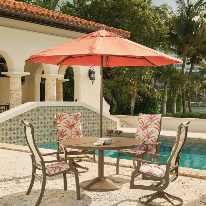 Telescope Casual Cascade dining table with swivel chairs under a coral umbrella by a pool