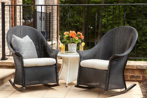 Two Lloyd Flanders Universal Loom high back porch rockers with a round end table on a terrace