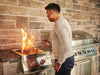 Searing a steak on the dual infrared burner beside a Built-In 700 Series grill