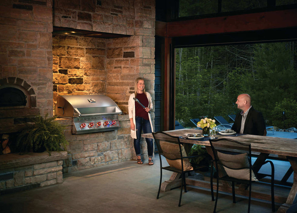 Built-In 700 Series 38 in a stone outdoor kitchen with a couple at dusk