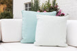 Aqua and white geometric Lloyd Flanders throw pillows on a white sofa