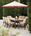 Telescope Casual Belle Isle cushion dining chairs around a Rustic Polymer dining table with an umbrella