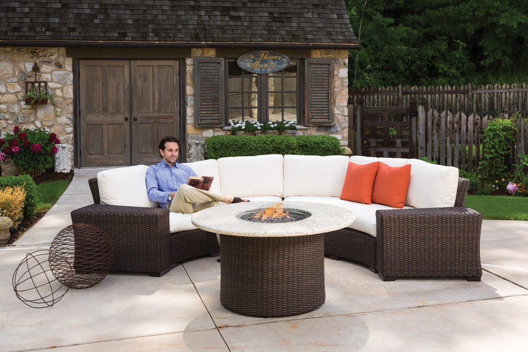 Lloyd Flanders Mesa curved sectional and round fire table on a stone patio