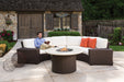Lloyd Flanders Mesa curved sectional and round fire table on a stone patio