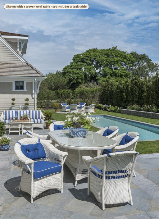 Lloyd Flanders Nantucket 7-Piece Teak Dining Set on a patio (Shown with a woven oval table · set includes a teak table)