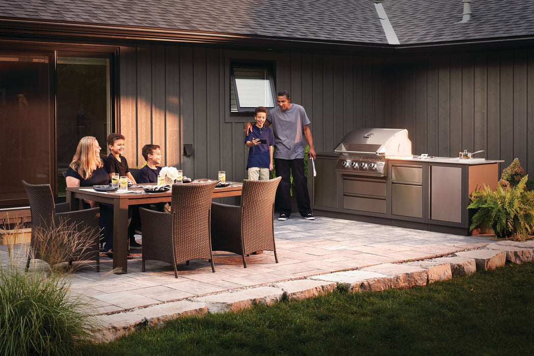 Family dinner on a stone patio with the Built-In 500 Series 32 in the outdoor kitchen