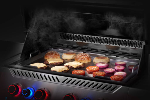 Napoleon stainless steel griddle insert with burgers and onions on a Prestige grill
