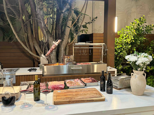 An asado spread beside a Tagwood BBQ08SS built into an outdoor kitchen