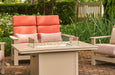 Telescope 36" x 54" fire table with the rectangular glass surround, flames lit, beside a coral cushioned loveseat