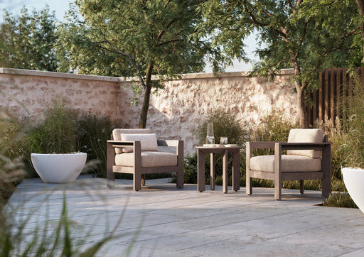 Woodard Beau 3-piece lounge set: two lounge chairs and a side table on a stone patio