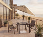 Woodard 7.5' Aluminum Market Umbrella with Push-Button Tilt in Champagne Bronze shown over a Woodard dining set