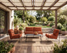 Woodard Reed 4-piece lounge set: sofa, two lounge chairs and coffee table with rust cushions on a covered patio