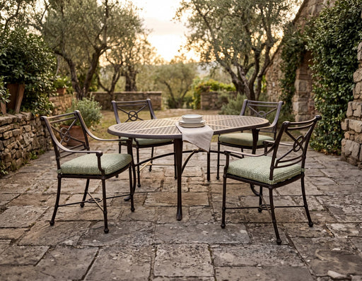 Woodard Hampton oval dining table on cabriole legs with four cushioned dining arm chairs in a stone courtyard