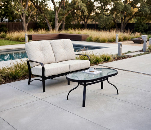Woodard Deluxe obscure glass oval coffee table with the Fremont love seat by a pool