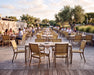 Woodard Profile sintered stone dining tables with sling dining chairs on a seaside restaurant terrace