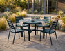 Four Woodard Daytona slat side chairs around a round Tri-Slat top Elite base dining table on a stone patio (table sold separately)