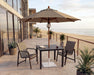 Woodard 9' Wood Market Umbrella with Pulley Lift in Teak Stain shown over a Woodard dining set
